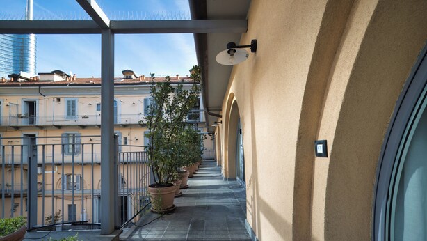 Un balcone con piante in vaso, una vista aperta sul cielo e un edificio sullo sfondo.