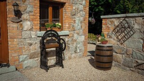 A stone building with a wooden door, a window with shutters, a vintage mechanical device, and a barrel. - Charming 1-bedroom cottage in Rathdrum with WiFi (Rathdrum)