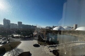 A cityscape with modern buildings, a park with a pond, and large white domes. - Qisheng Internation Hotel (Zibo)