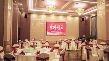 A banquet hall with round tables, white tablecloths, and red sashes.