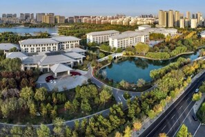 An aerial view of a modern residential complex with multiple buildings, a central water feature, and a well-maintained landscape. - Qisheng Internation Hotel (Zibo)