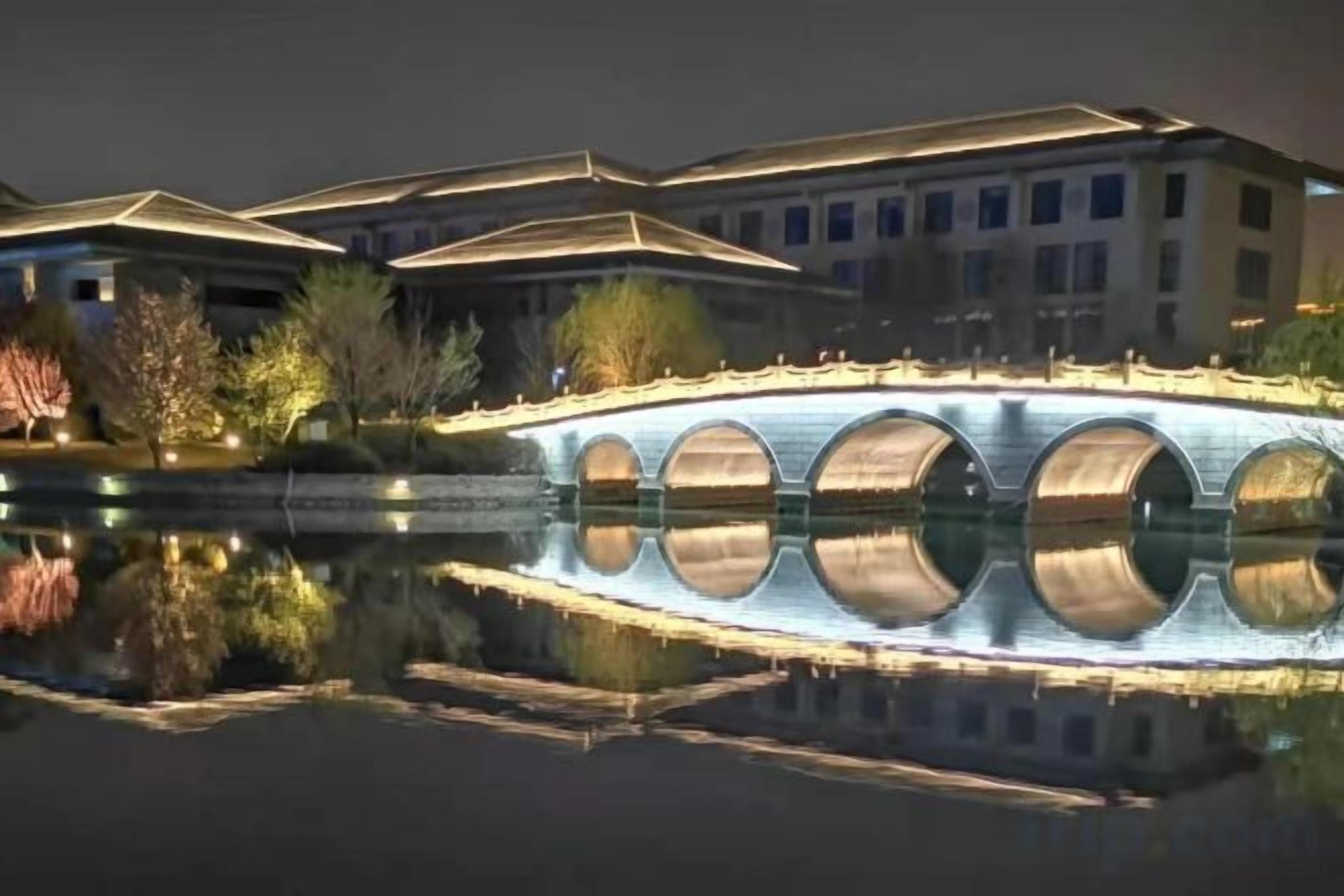 Un pont enjambant une étendue d’eau, avec des bâtiments en arrière-plan.