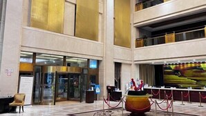 A spacious lobby with a reception desk, a large digital screen, and a decorative fountain. - Qisheng Internation Hotel (Zibo)