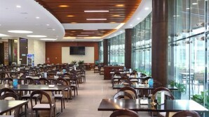 A spacious restaurant with multiple tables and chairs, a modern ceiling design, and large windows allowing natural light. - Qisheng Internation Hotel (Zibo)