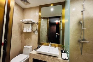 A bathroom with a white sink, a mirror, a shower, and a toilet. - Qisheng Internation Hotel (Zibo)