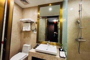 Un baño con lavamanos blanco, un espejo, ducha y retrete.