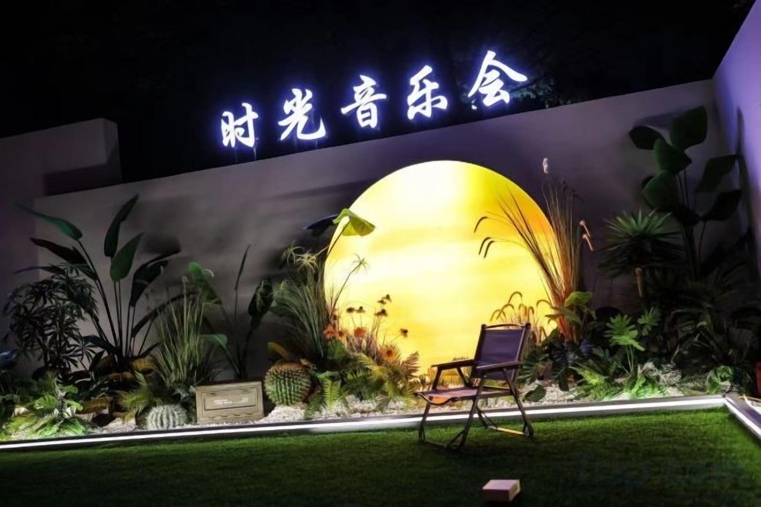 A well-lit outdoor area with a large illuminated sphere, seating, and a wall with signage.