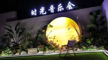A well-lit outdoor area with a large illuminated sphere, seating, and a wall with signage.