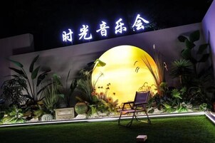 Un espacio exterior bien iluminado con una gran esfera iluminada, asientos y una pared con señalización.