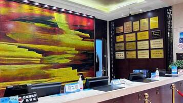 A reception desk with a large abstract painting, a wall of framed certificates, and a counter with a digital display.