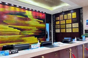 Una recepción con un cuadro abstracto grande, una pared de certificados enmarcados y un mostrador con pantalla digital.