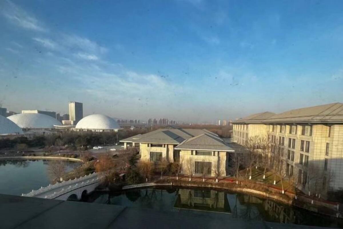 A view of a building complex with large domed structures, a bridge, and a body of water.