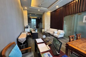 Habitación de hotel con una mesa de comedor, un sofá, una computadora portátil y un televisor.