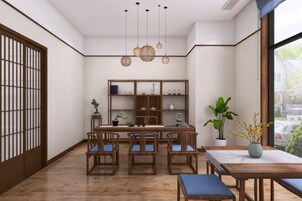 Una habitación tradicional japonesa con suelo de tatami, una mesa de madera baja con sillas, una estantería y un ventanal grande.