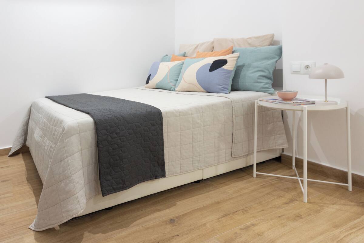 A neatly arranged bedroom with a bed, bedside table, and a lamp.