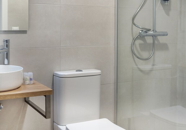 Een moderne badkamer met een wit toilet, een groot wit wastafel en een douchecabine van glas.