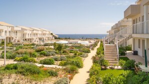 Een resort met meerlaags gebouwen, een centraal pad en uitzicht op zee.