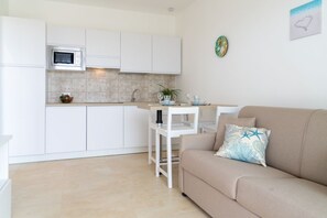 A modern kitchen with white cabinets, a microwave, and a dining area with a white table and chairs.