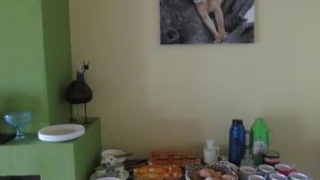 Un espace repas agrémenté d’un mur vert, d’un tableau encadré représentant une lionne, ainsi que de divers aliments et boissons disposés sur le comptoir.