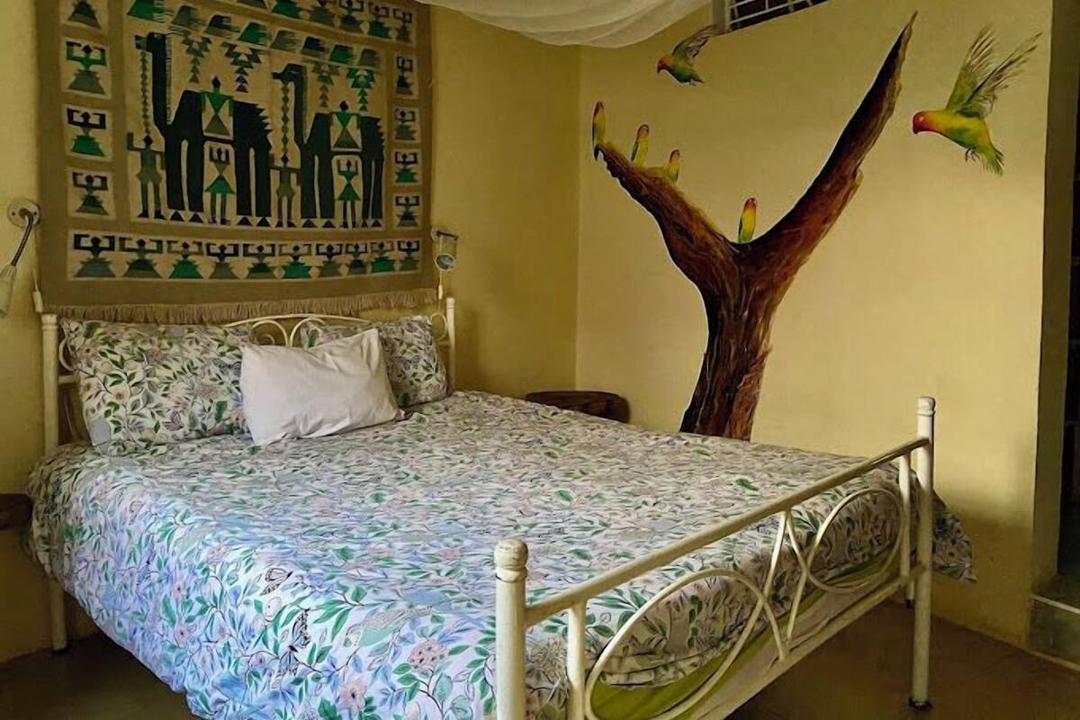 Une chambre à coucher avec un lit, une peinture murale et une fenêtre.