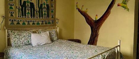 A bedroom with a bed, a wall mural, and a window.