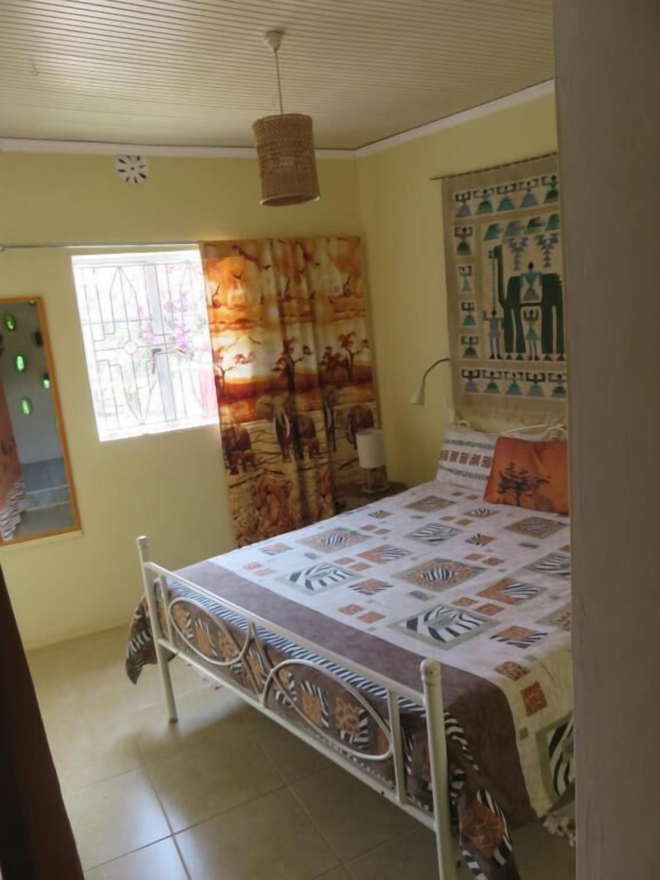 Une chambre à coucher avec un lit, une fenêtre, un rideau et un élément de décoration murale.