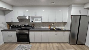 Een moderne keuken met witte kastjes, een roestvrijstalen koelkast, een magnetron en een fornuis.
