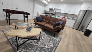 Een moderne woonkamer met een bruine leren bank, twee bijzettafels met glazen blad en een tapijt met dessin.