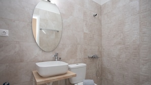 A modern bathroom with a white sink, toilet, and shower. - Captain Antonis - Authentic Seafront Living in Gerolimenas (Gerolimenas)