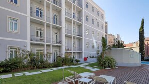 Un hotel de varios pisos con balcones, piscina y zona de estar al aire libre.