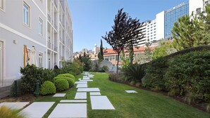 Un camino de jardín bien cuidado con setos ordenados y un cielo despejado.