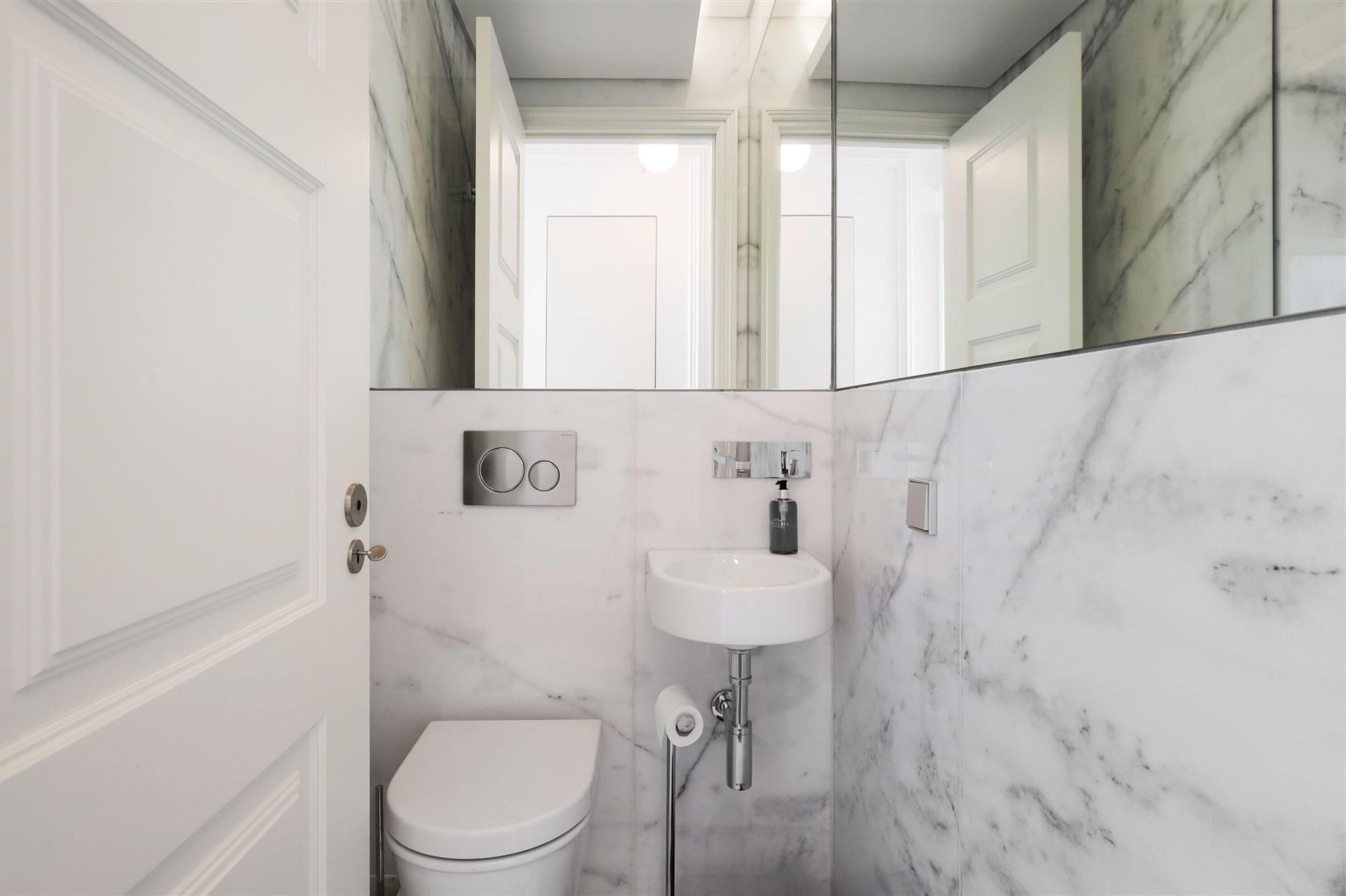 A bathroom with a toilet, a sink, and a mirror.