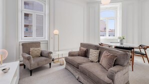 Un salón amplio con un sofá gris, un sillón y una mesa de comedor con sillas.