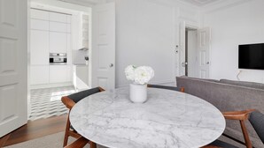 Una cocina moderna con armarios blancos, encimera de mármol y horno empotrado.