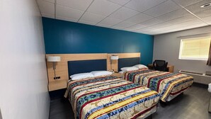 Habitación de hotel con dos camas, cada una con una colcha estampada, cabecero de madera y lámparas de noche.