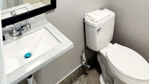 Un baño con lavamanos blanco, inodoro y perchero con toallas.