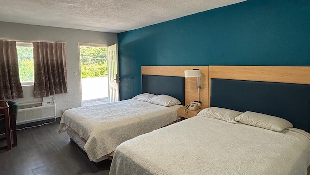 Habitación de hotel con dos camas, un escritorio y una ventana con cortinas.