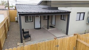 Un patio cubierto con cerca de madera, una puerta y un pequeño rincón de estar.