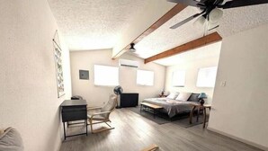 Un dormitorio compacto con cama, escritorio, silla y ventilador de techo.