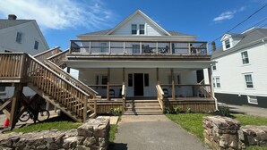 A two-story house with a wooden deck and a stone pathway leading to the front door. - Cozy 2-Bed Apartment in Town (Wolfville)
