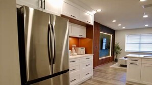 A modern kitchen with stainless steel appliances, white cabinetry, and a wooden floor.