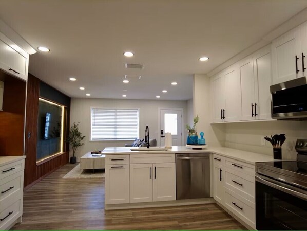 A modern kitchen with white cabinets, a stainless steel dishwasher, and a built-in oven.