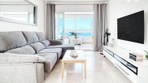A modern living room with a grey sectional sofa, a wooden coffee table, and a large flat-screen TV on a white console. - Siroco-Gemelos 22 (Benidorm)