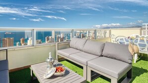 A balcony with a sofa, a table with a fruit bowl, and a glass of water. - Siroco-Gemelos 22 (Benidorm)