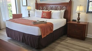 A hotel room with a large bed, a ceiling fan, two bedside lamps, a wooden nightstand, and a wooden dresser. - Cozy 2-bedroom condo with WiFi, AC in Orlando - Close to Universal and Disney (Orlando)