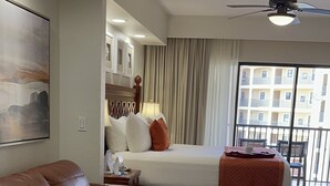 A modern hotel room with a large bed, a leather sofa, a dining table, and a balcony with a view of the city. - Cozy 2-bedroom condo with WiFi, AC in Orlando - Close to Universal and Disney (Orlando)