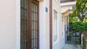 Un camí de pedra estret que condueix a un edifici amb una porta de fusta gran i un senyal amb el número '75'.