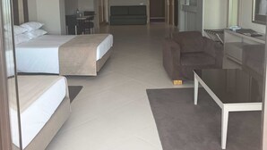 A hotel room with two beds, a sofa, a coffee table, and a TV.