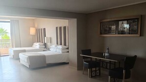 Amplia habitación de hotel con una cama grande, un área de comedor con mesa y sillas, y un cuadro enmarcado en la pared.