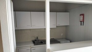 A kitchen with white cabinets, a sink, and a fire extinguisher on the wall.